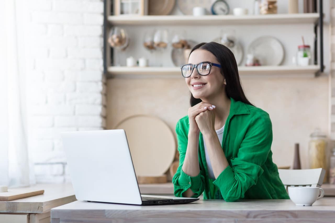 woman in green smiling by computer